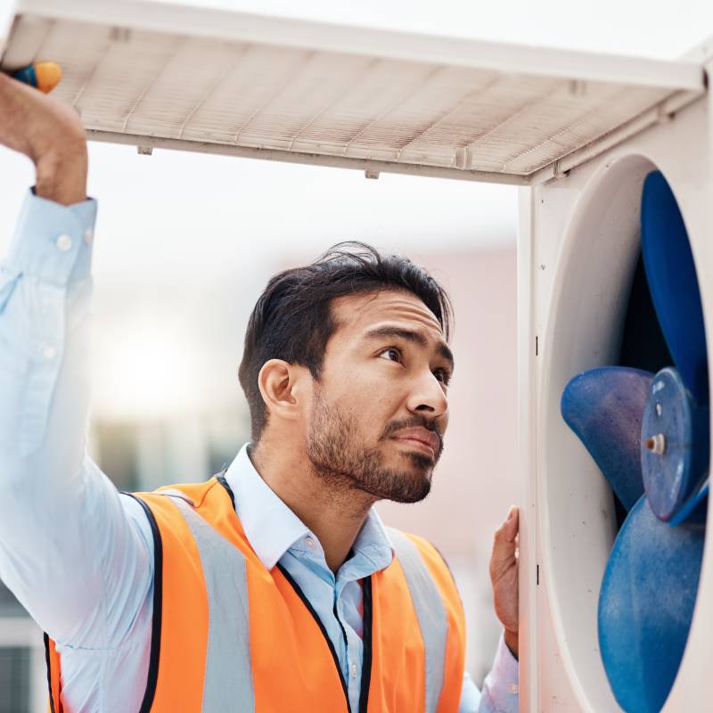 HVAC technician inspecting an air conditioning unit outdoors